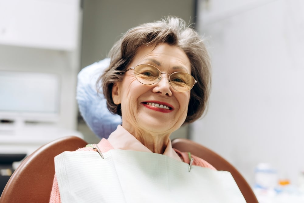 Implant-Supported Dentures in Knoxville: a smiling older woman in a dental chair